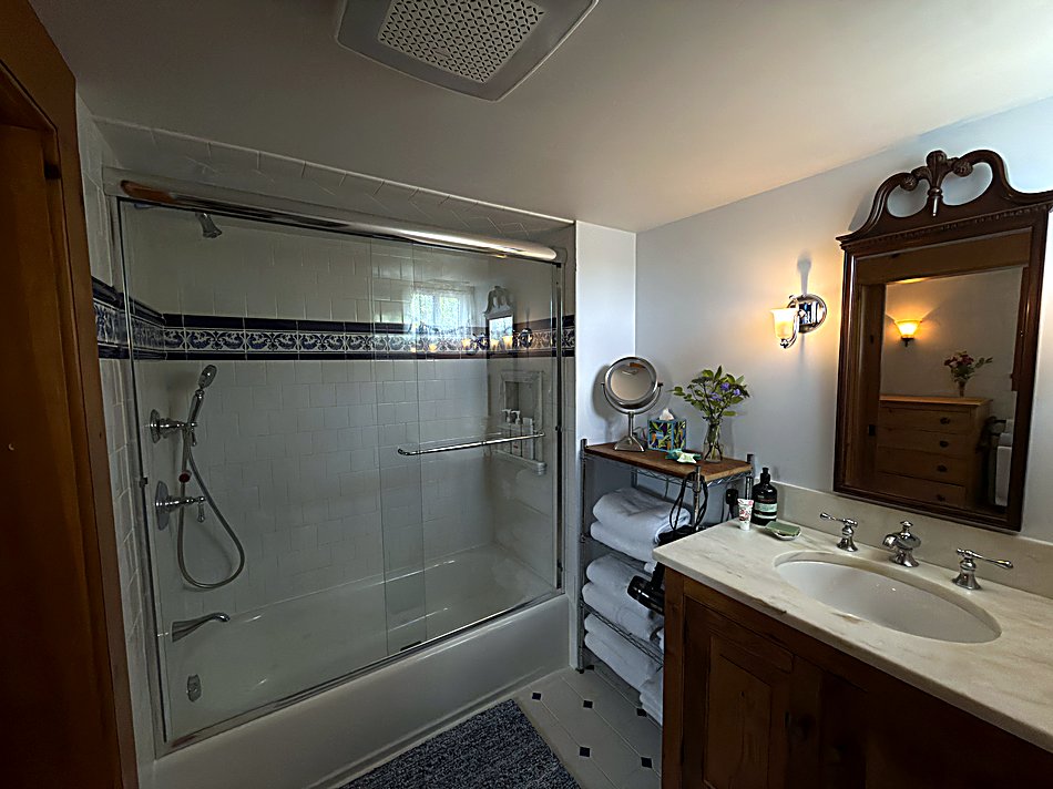 The full bathroom with subway tile and a marble-topped vanity